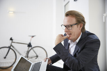 Pensive businessman with laptop - RHF001635