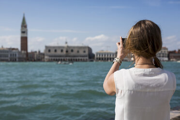 Italy, Venice, Tourist taking pictures with smart phone - MAUF000653