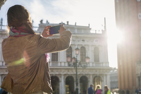 Italien, Venedig, Tourist nimmt Bilder mit Smartphone gegen die Sonne, lizenzfreies Stockfoto