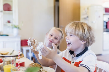 Happy boy at table smeared with chocolate marshmallow - MJF001840