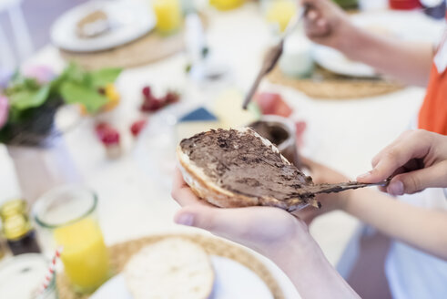 Kind schmiert Schokoladenaufstrich auf Brot - MJF001844