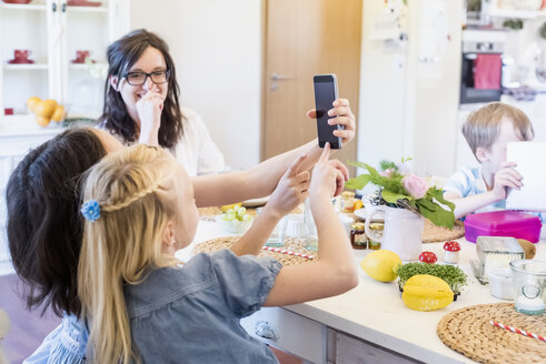 Zwei Mädchen benutzen Smartphone am Tisch - MJF001867