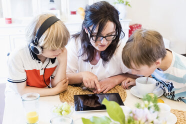 Mutter und zwei Jungen teilen sich ein digitales Tablet - MJF001871