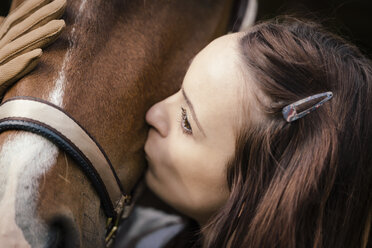 Junge Frau küsst braunes Pferd - MIDF000730