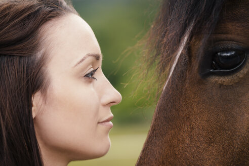 Junge Frau und braunes Pferd von Angesicht zu Angesicht - MIDF000735