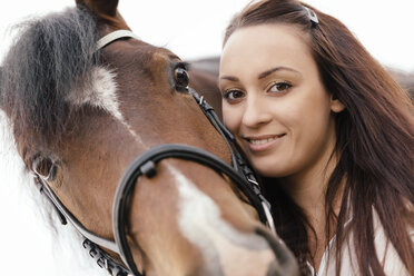 Portrait of smiling young woman with brown horse - MIDF000737