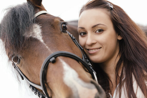 Porträt einer lächelnden jungen Frau mit braunem Pferd - MIDF000737