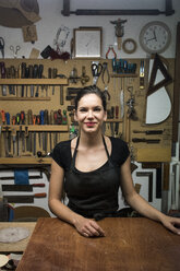 Porträt einer lächelnden Geigenbauerin in ihrer Werkstatt - ABZF000709