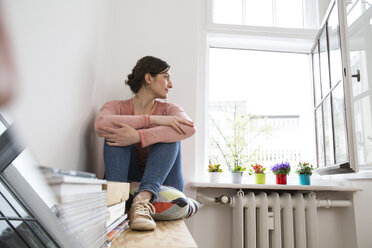 Young woman sitting at the window looking out - FKF001844