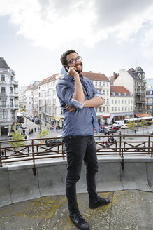 Junger Mann am Handy auf der Dachterrasse - FKF001859