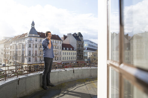 Young man on cell phone on roof terrace - FKF001886