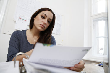 Frau bei der Arbeit an Akten am Bürotisch - FKF001893