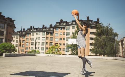 Junge Frau, die auf einen Basketballkorb zielt, lizenzfreies Stockfoto