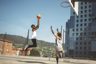 Junges Paar spielt Basketball auf dem Platz - DAPF000158