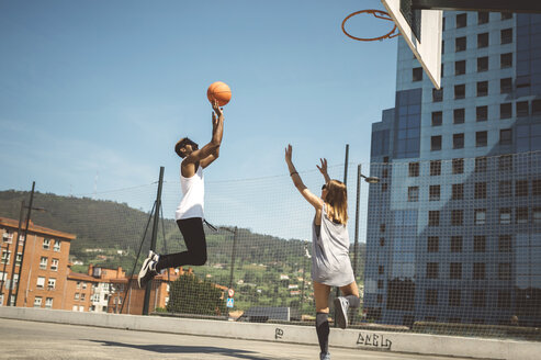 Junges Paar spielt Basketball auf dem Platz - DAPF000158