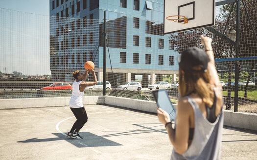 Junge Frau mit digitalem Tablet im Gespräch mit einem Basketballspieler - DAPF000161