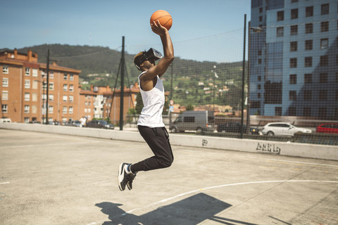 Junger Mann spielt Basketball mit Virtual-Reality-Brille, lizenzfreies Stockfoto