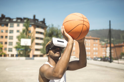 Young man playing basketball with virtual reality glasses on - DAPF000170