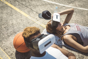 Junges Paar, das eine Virtual-Reality-Brille benutzt und den Kopf auf einem Basketball ablegt - DAPF000171