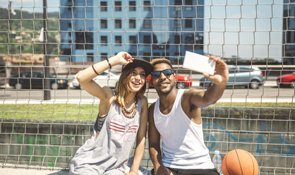 Junges Paar macht Selfie auf dem Basketballplatz - DAPF000175