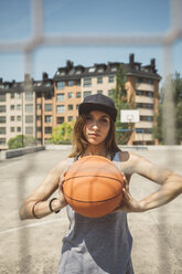 Junge Frau mit Mütze hält Basketball - DAPF000180