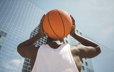 Junger Mann hält Basketball hinter seinem Kopf - DAPF000192