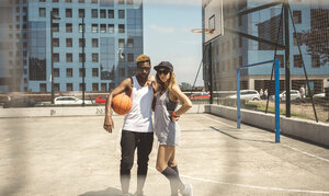 Junges Paar steht auf einem Basketballfeld und schaut in die Kamera - DAPF000194