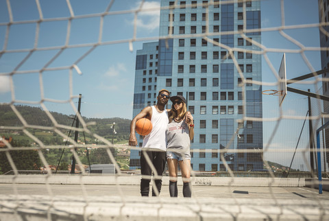 Young couple standing on basketball field, looking at camera stock photo