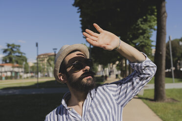 Junger Mann mit Hut und Sonnenbrille, der seine Augen abschirmt - FMOF000004