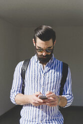 Bearded young man looking at his smartphone - FMOF000010