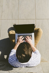 Young man sitting on the ground using laptop - FMOF000016
