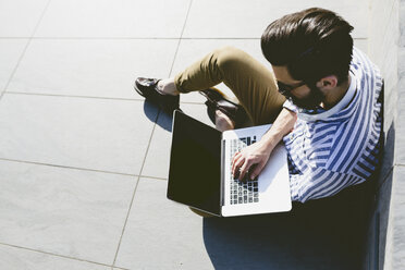 Young man sitting on the ground using laptop - FMOF000019