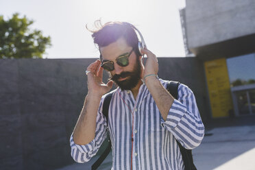Bearded young man with sunglasses listening music with headphones - FMOF000020