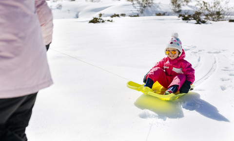 Girl sitting on sledge, mother pulling stock photo