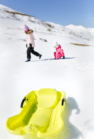 Spanien, Asturien, Kinder spielen im Schnee, Schlitten im Vordergrund, lizenzfreies Stockfoto