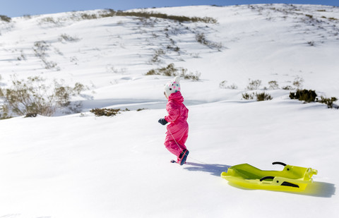 Spain, Asturias, girl with sledge in the snow stock photo