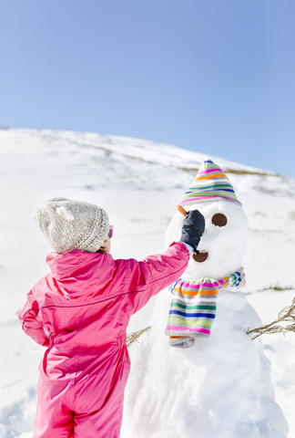 Mädchen baut einen Schneemann im Winter, lizenzfreies Stockfoto