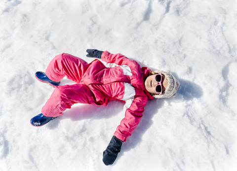 Kleines Mädchen spielt im Schnee, liegend, lizenzfreies Stockfoto