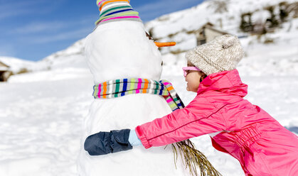 Mädchen spielt mit Schneemännern im Winter - MGOF001974
