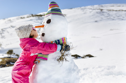 Mädchen spielt mit Schneemännern im Winter, lizenzfreies Stockfoto