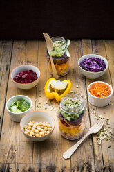 Two glasses of rainbow salad with chick-peas, sprouts and different vegetables and bowls with ingredients - LVF004973