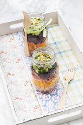 Two glasses of rainbow salad with chick-peas and different vegetables on wooden tray - LVF004976