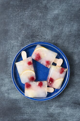 Hausgemachte Holunderblüten-Zitronen-Himbeer-Eislutscher auf einem Teller - MYF001571