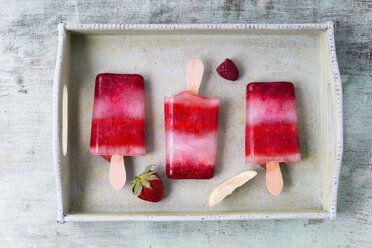 Homemade strawberry raspberry lemon ice lollies on tray - MYF001573