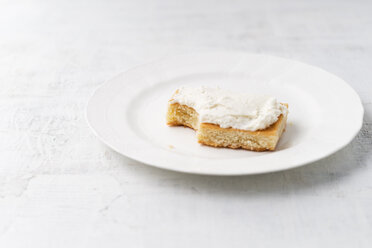 Lemon cake with curd cream on white plate, bitten - MYF001583