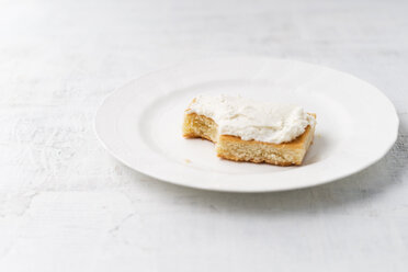 Zitronenkuchen mit Quarkcreme auf weißem Teller, angebissen - MYF001583