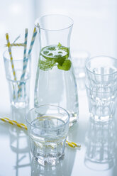 Glasflasche mit Zitronenmelisse aromatisiertes Wasser und verschiedene Gläser - OJF000143