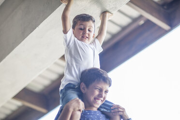 Little boy sitting on his brother's shoulders - ZEF008735