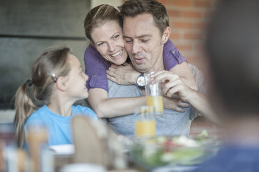 Glückliche Frau, die ihren Mann umarmt, während die Kinder sie anschauen - ZEF008746