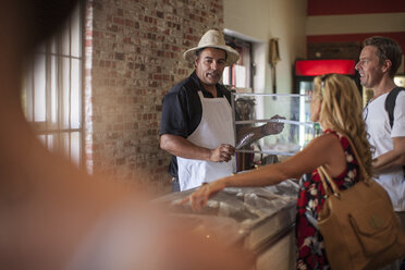 Shopkeeper in shop helping clients - ZEF008788